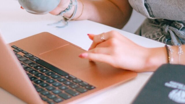 A woman sitting at a laptop with a cup of coffee