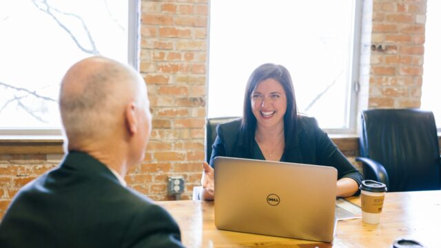 woman in a business meeting sits smiling facing the camera